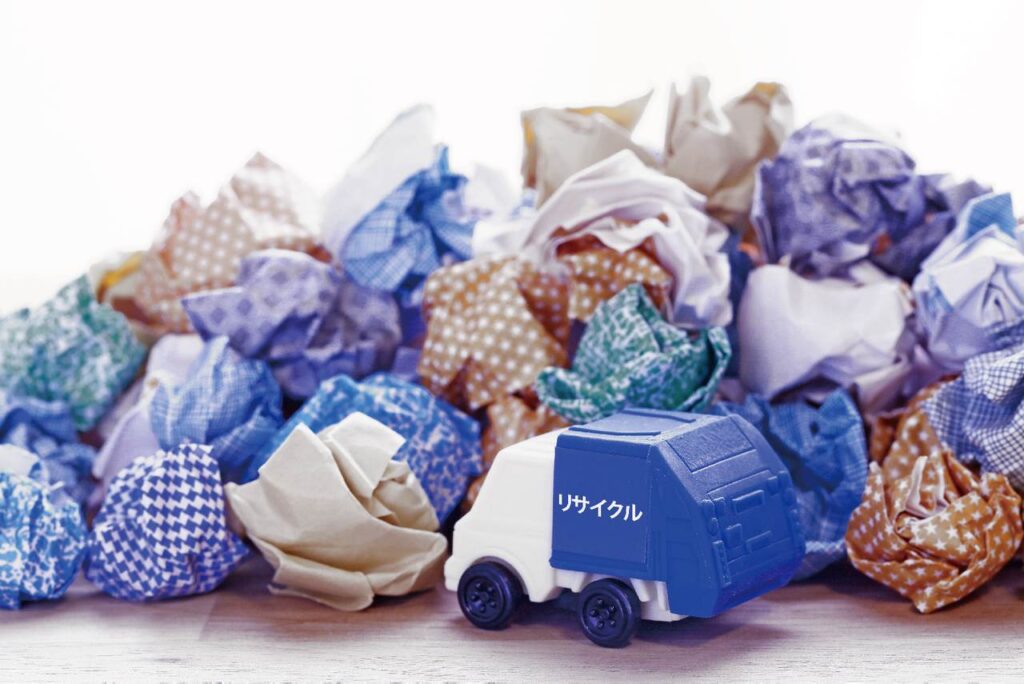 リサイクルと書かれたゴミ収集車が紙くずを収集している様子